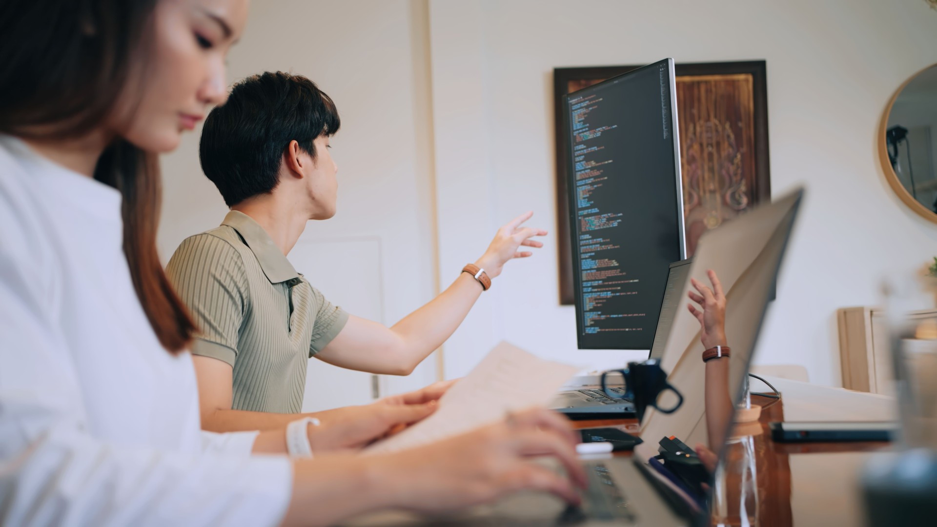 A professional working from home, debugging code on a laptop and monitor. A cozy and efficient workspace for remote tech projects.